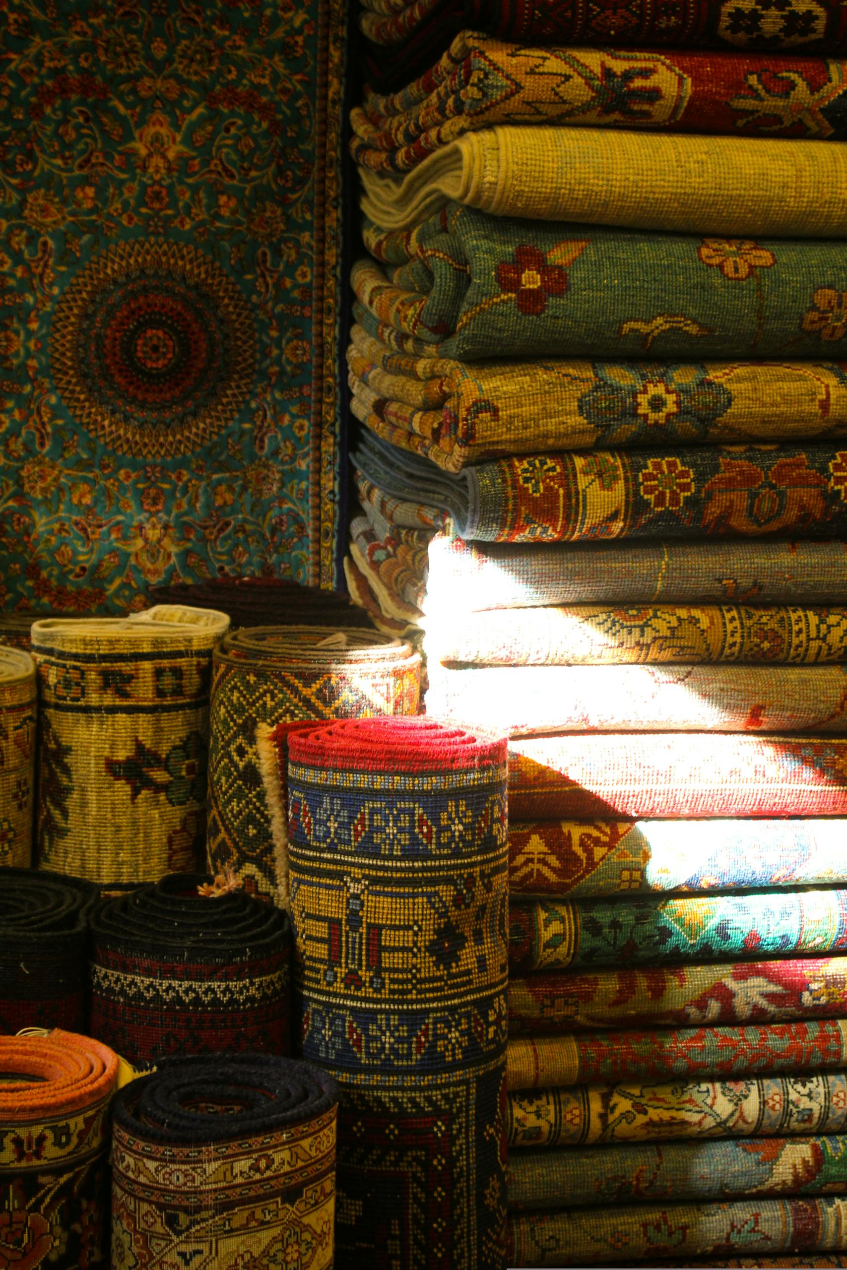Elegant display of diverse Oriental rugs in rolled and stacked arrangements.