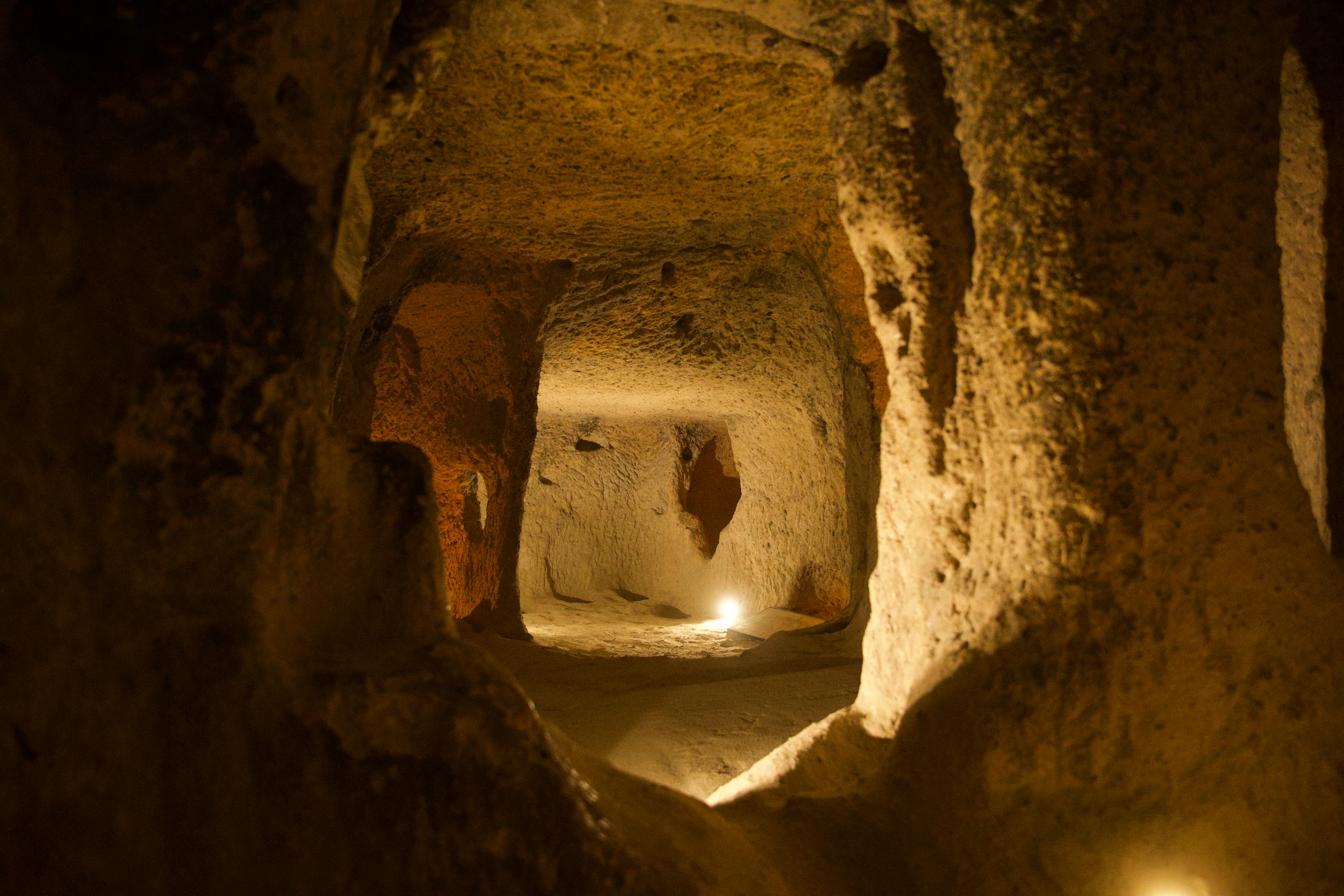 Explore the dimly lit passage of an ancient underground cave with textured stone walls.