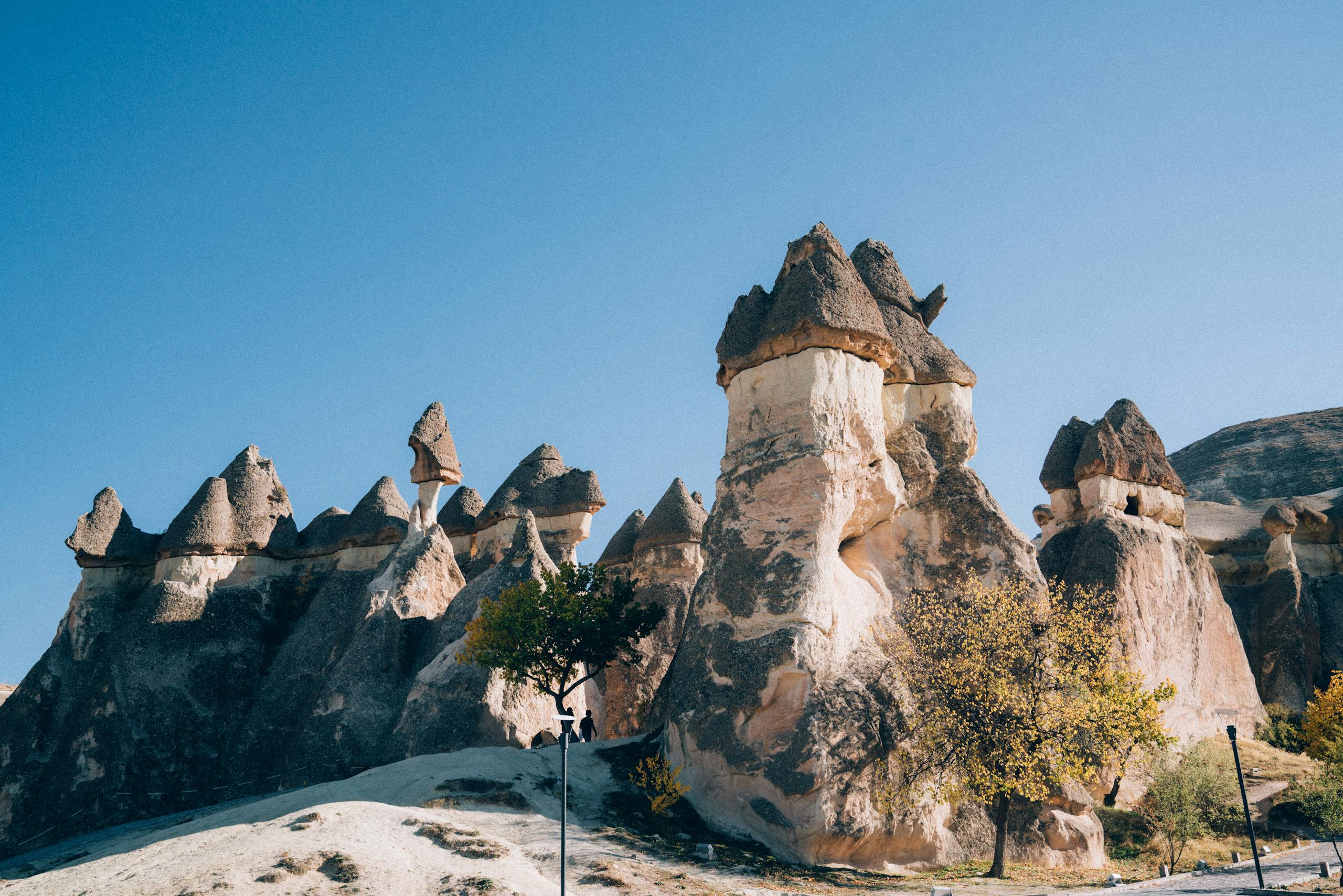 Scenic view of Cappadocia's unique fairy chimney rock formations under a clear blue sky.